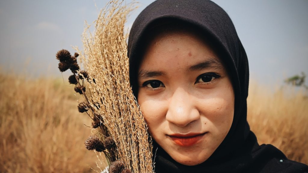 Ethic woman with bunch of dry grass in field